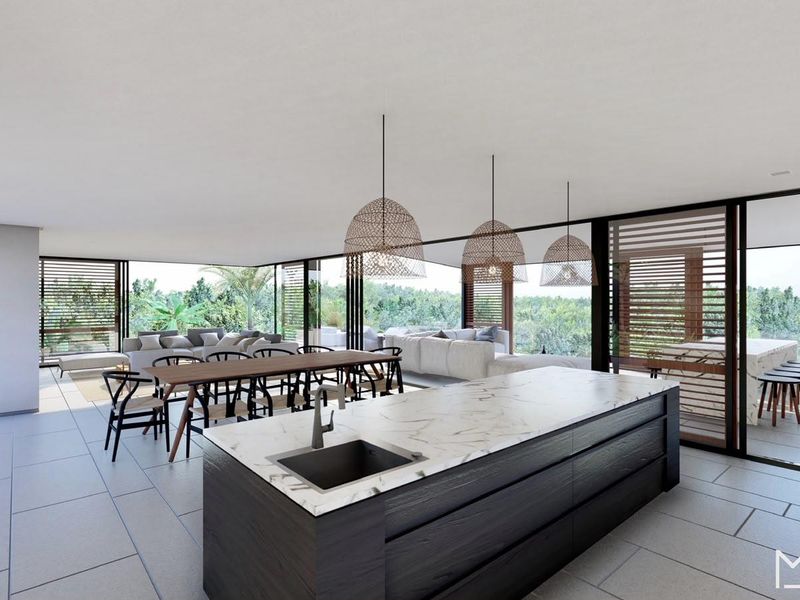 Spacious open-plan living area featuring a modern kitchen island with marble countertop, seamless indoor-outdoor flow through large sliding glass doors, and contemporary finishes.