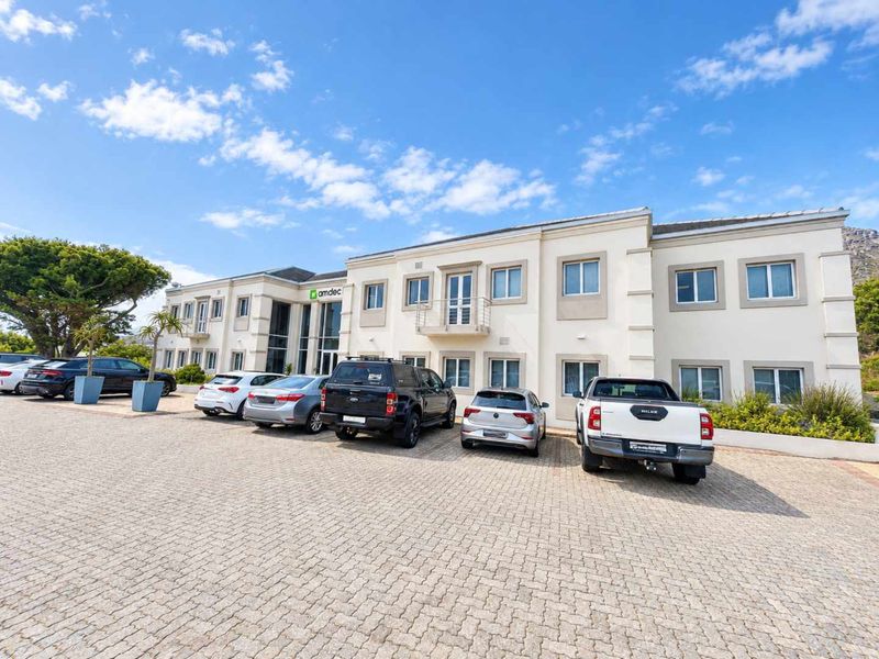 A well-maintained double-storey office building featuring a paved parking area and a prominent glass entrance facade.