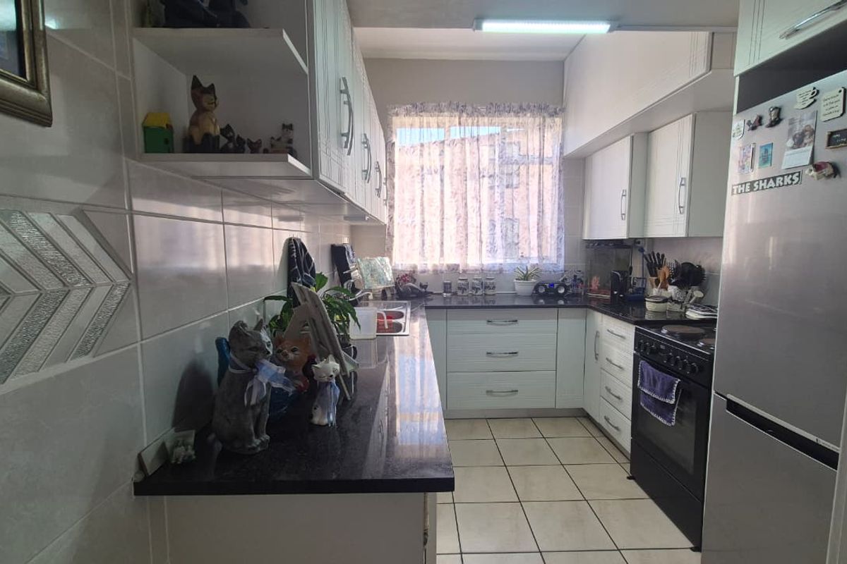 A functional kitchen featuring granite countertops, white cabinetry, tiled walls, and ceramic flooring, offering a practical layout for daily meal preparation.