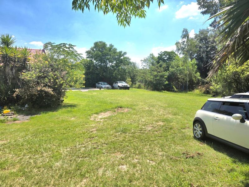 A spacious, open garden area featuring a large lawn and mature trees, providing a natural outdoor setting for the property.