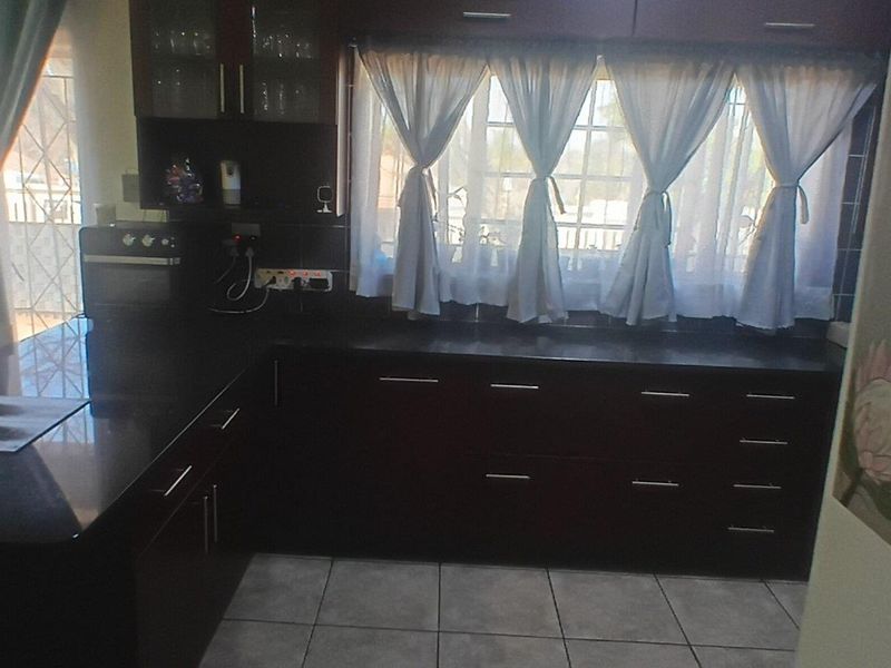 A functional kitchen featuring dark wood cabinetry, granite countertops, and a built-in oven, with tiled flooring and natural light from the window.