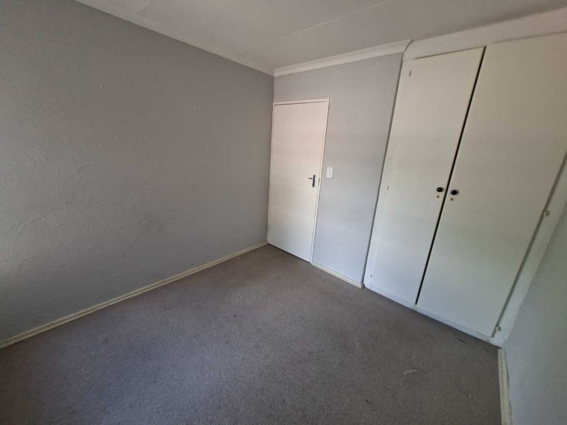 An empty bedroom featuring built-in cupboards, carpeted flooring, and coved ceilings, offering a blank canvas for personalization.