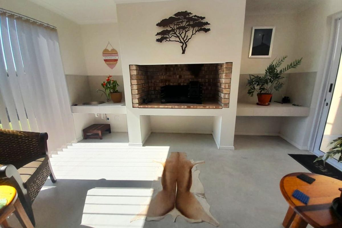An indoor entertainment area featuring a built-in brick fireplace, concrete flooring, and a dedicated prep area with a sink.