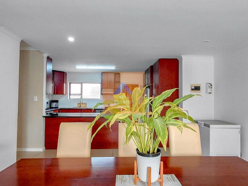 Open plan living and dining area featuring a kitchen with dark wood cabinetry, granite countertops, and tiled flooring.