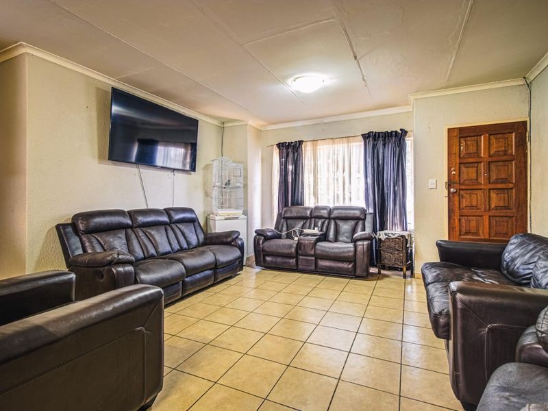 A spacious living room featuring tiled flooring and a coved ceiling, providing a functional base for comfortable family living.