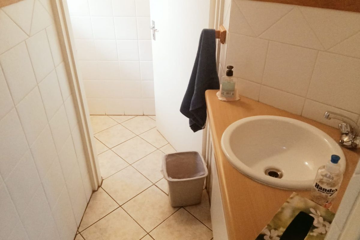 A functional bathroom featuring a corner vanity with a built-in sink, tiled walls, and tiled flooring.