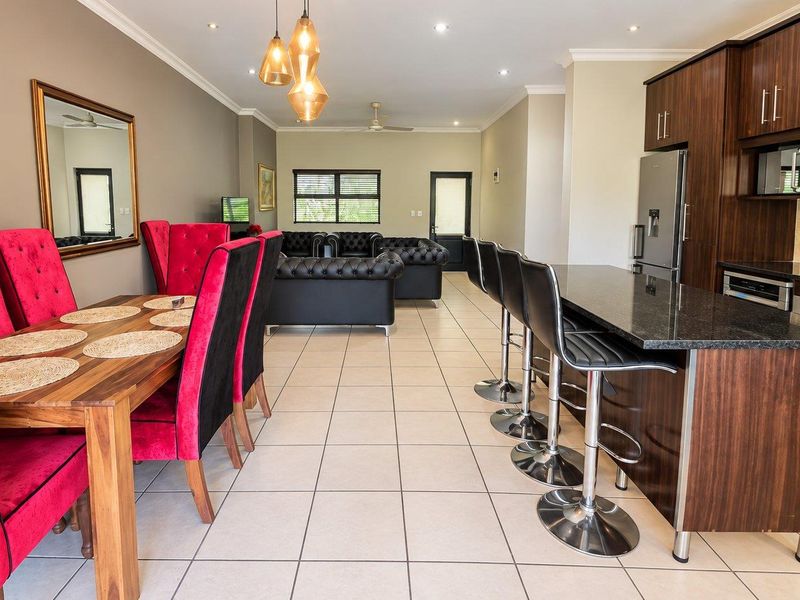 Spacious open-plan living area featuring a modern kitchen with granite countertops, dark wood cabinetry, and integrated appliances, flowing into the dining and lounge space.