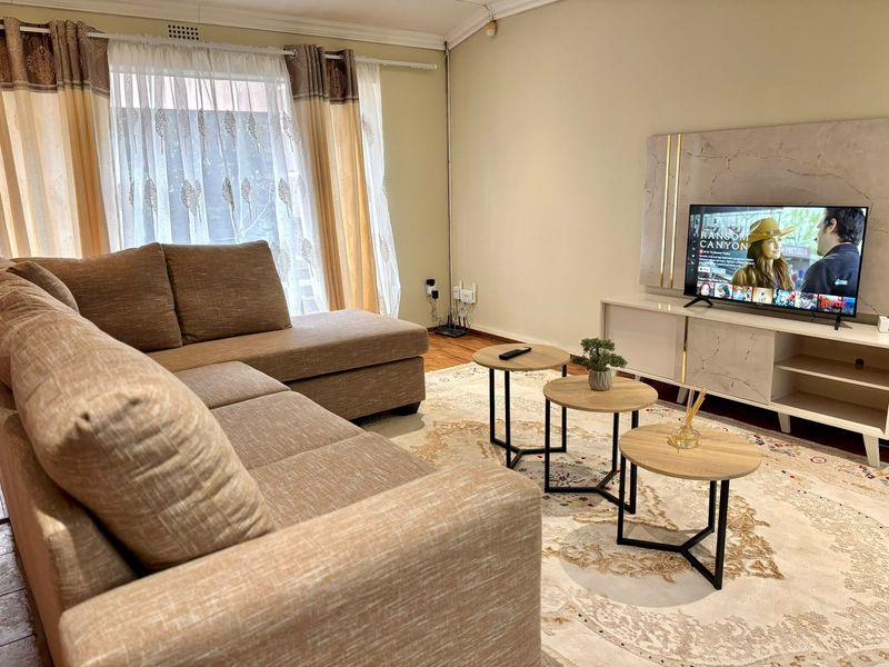A comfortable living room featuring laminate flooring and decorative cove cornicing, providing a neutral and inviting space for relaxation.