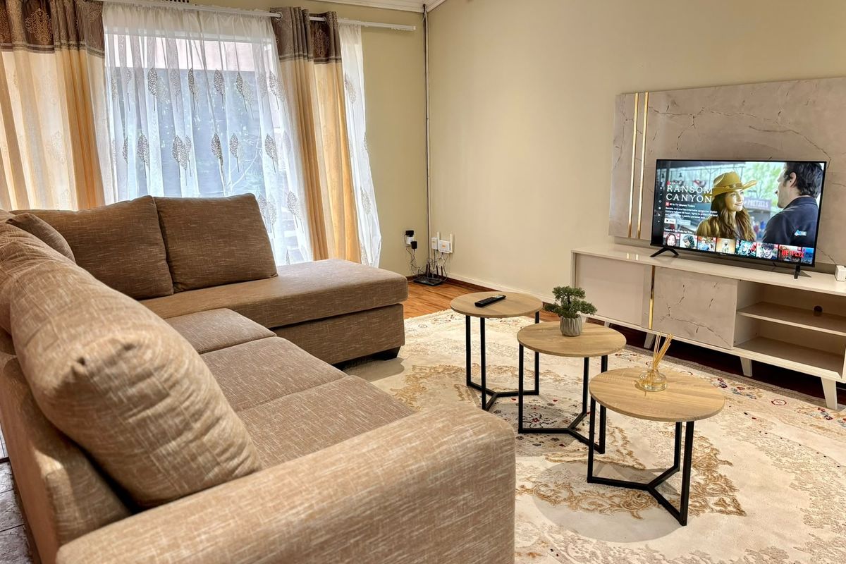 A comfortable living room featuring laminate flooring and decorative cove cornicing, providing a neutral and inviting space for relaxation.