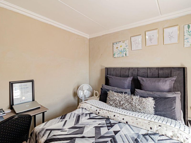 A bedroom featuring neutral wall tones and decorative crown molding, providing a functional space for rest and study.