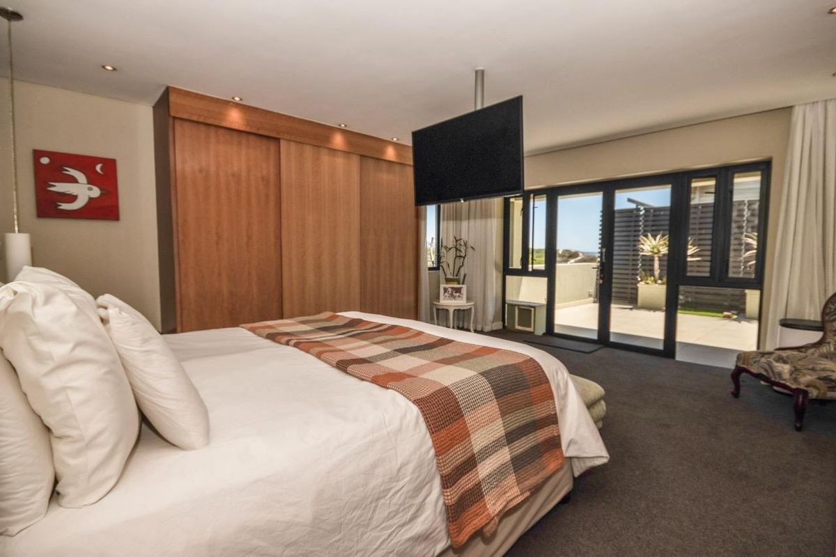 Spacious bedroom featuring built-in wooden wardrobes, recessed ceiling lighting, and large sliding glass doors providing direct access to a private patio area.