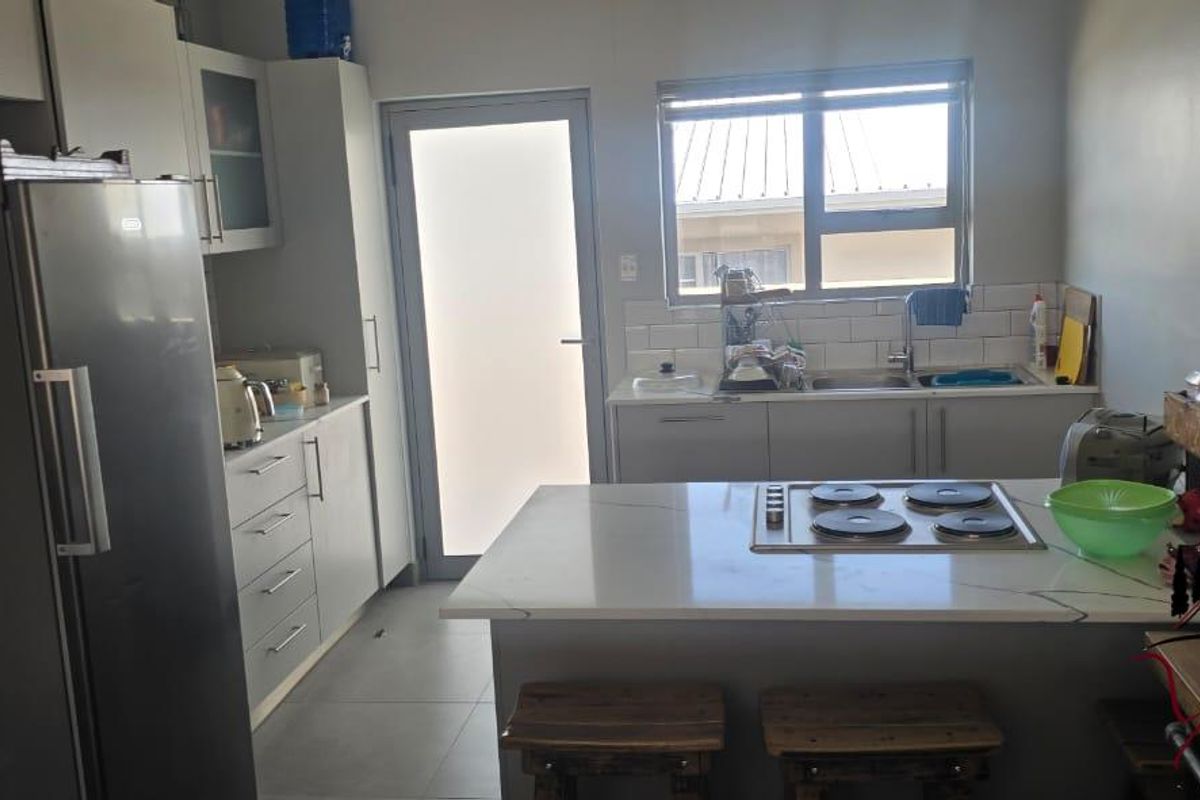 Modern kitchen featuring stone countertops, a built-in electric hob, subway tile backsplash, and ample cabinetry with a functional layout.