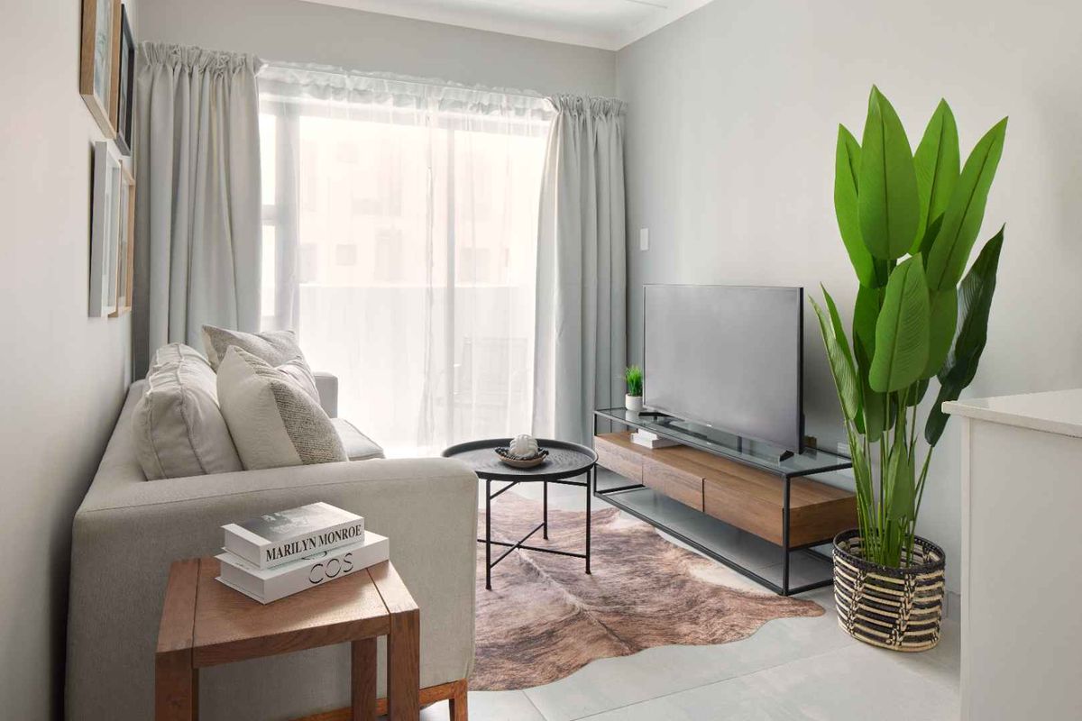 A bright and modern living room featuring neutral walls, tiled flooring, and a large sliding glass door providing natural light.