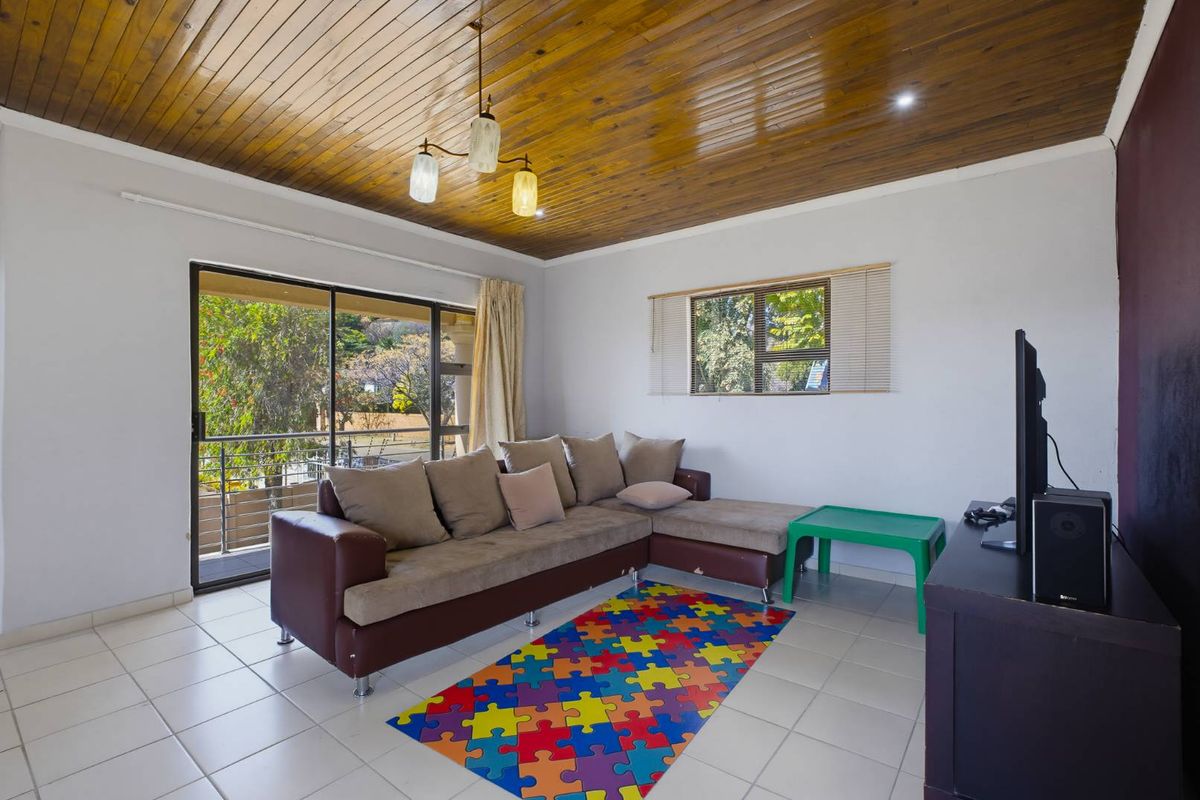 A living room featuring a distinctive timber-clad ceiling, tiled flooring, and a sliding glass door providing access to an outdoor area.
