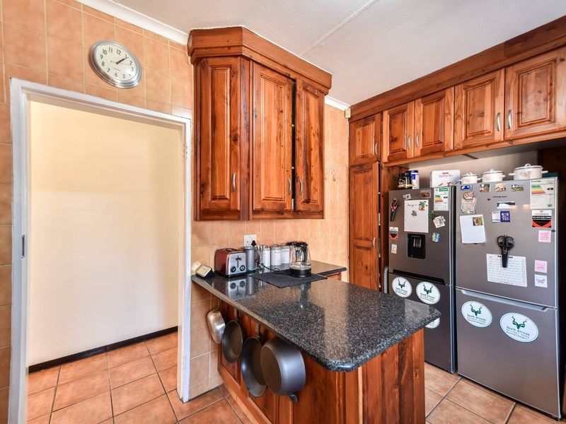 A functional kitchen featuring traditional wooden cabinetry, granite countertops, and tiled finishes, offering a classic aesthetic with ample storage space.