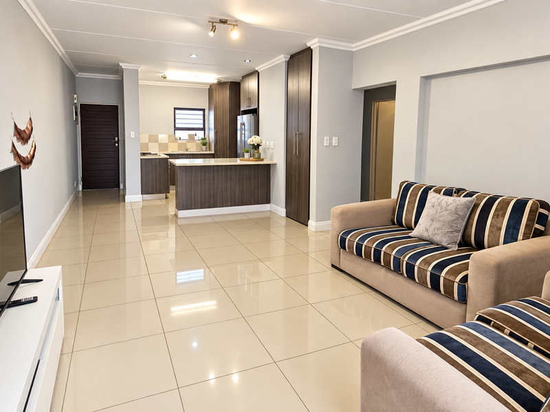 Spacious open-plan living area featuring polished tile flooring, modern kitchen cabinetry with an island, and neutral wall finishes throughout.