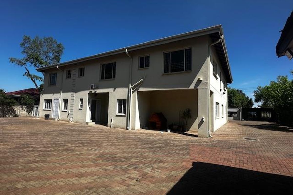 A view of the rear exterior of the property, featuring a paved courtyard area and a multi-story building structure.