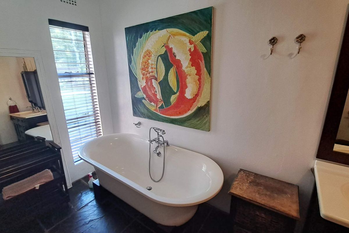 A well-appointed bathroom featuring a classic freestanding bathtub, slate flooring, and a built-in vanity, offering a blend of traditional style and functional design.