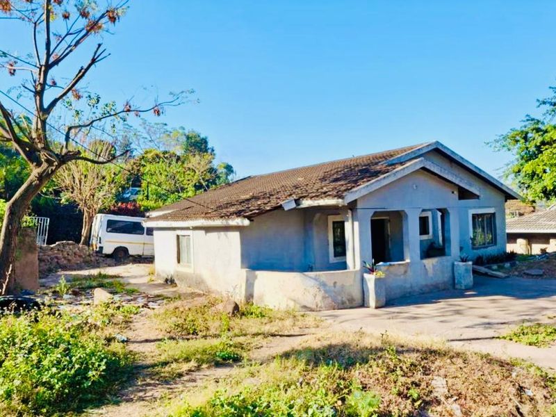 Front view of a single-story detached house featuring a tiled roof, concrete driveway, and a covered porch area requiring exterior maintenance and landscaping.