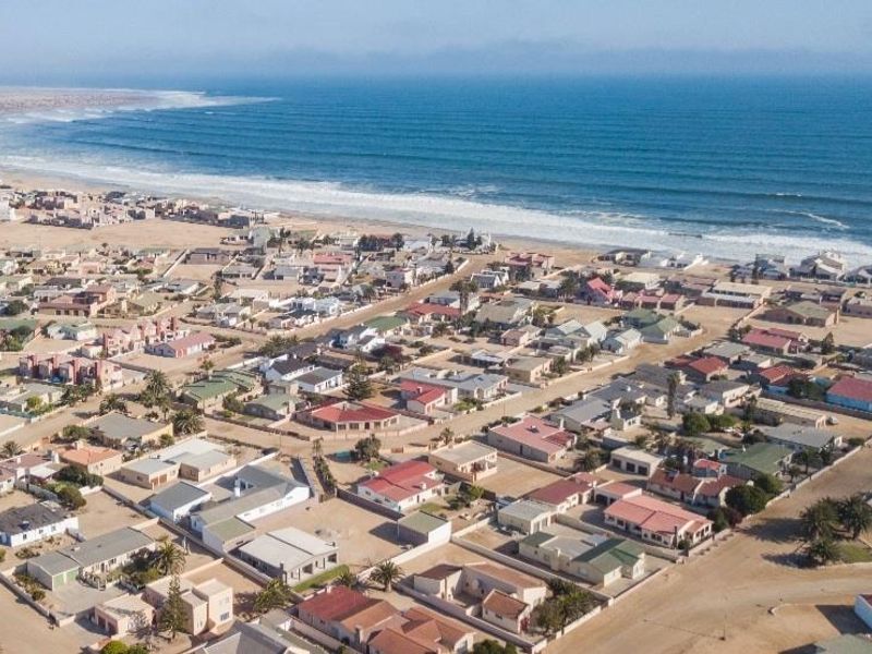 An aerial view of a coastal residential neighborhood situated along the shoreline, showcasing the proximity of the properties to the ocean.