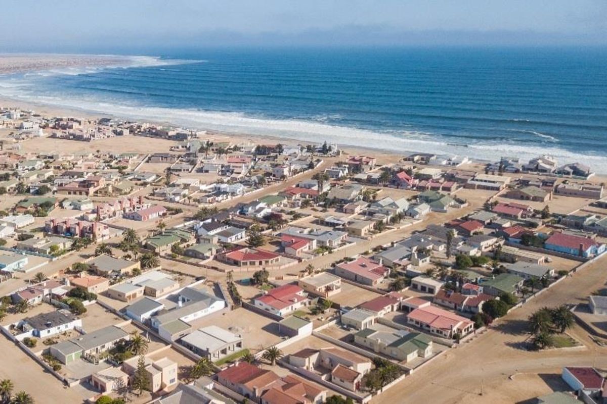 An aerial view of a coastal residential neighborhood situated along the shoreline, showcasing the proximity of the properties to the ocean.