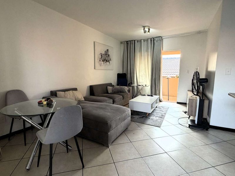 Open-plan living area featuring tiled flooring and a breakfast bar, with direct access to an outdoor balcony space.