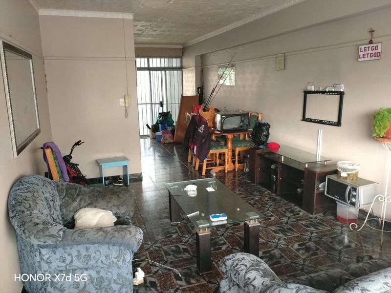A living room area featuring tiled flooring and a security gate, requiring cosmetic updates to improve the overall condition and appeal of the space.