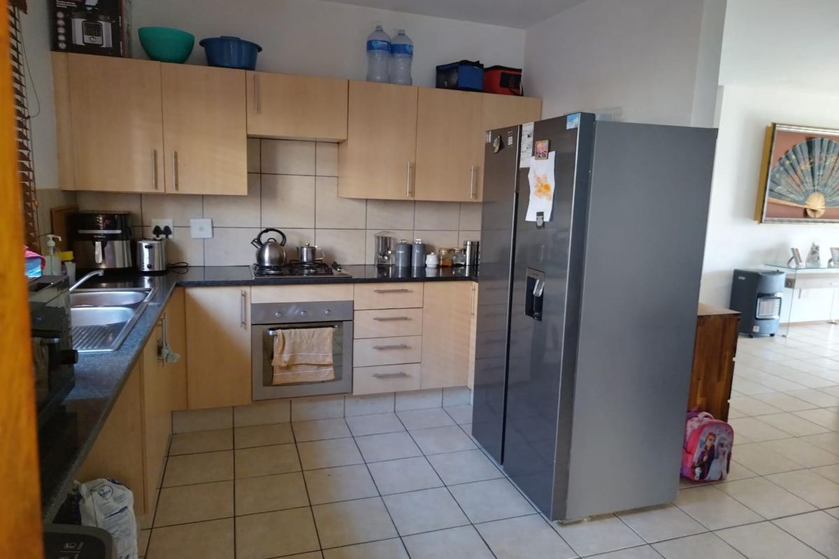 Functional kitchen featuring light wood-finish cabinetry, granite countertops, built-in oven, gas hob, and tiled flooring, offering a practical layout for daily use.