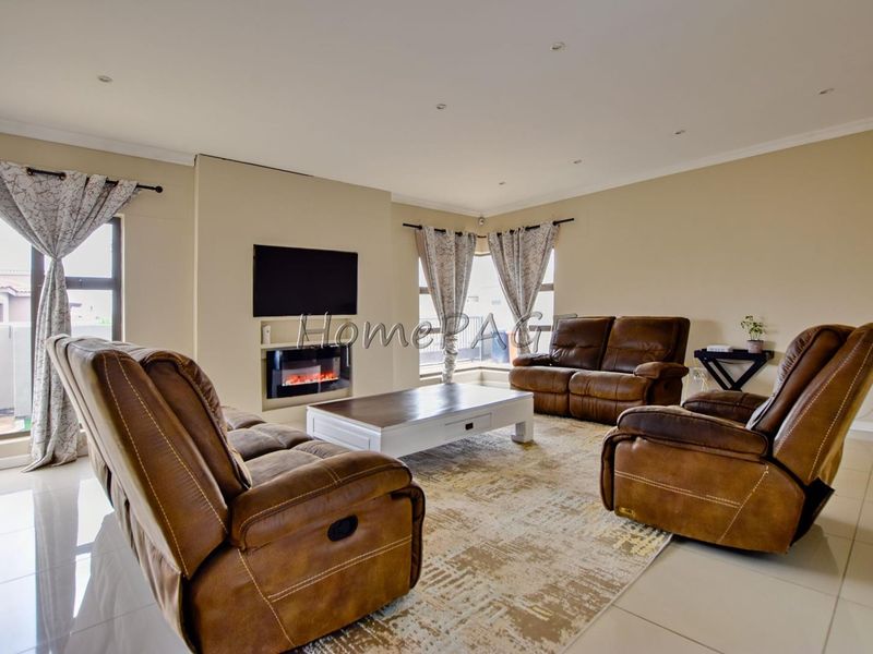 Spacious living room featuring tiled flooring, recessed downlights, and a modern built-in electric fireplace, offering a comfortable and well-lit area.