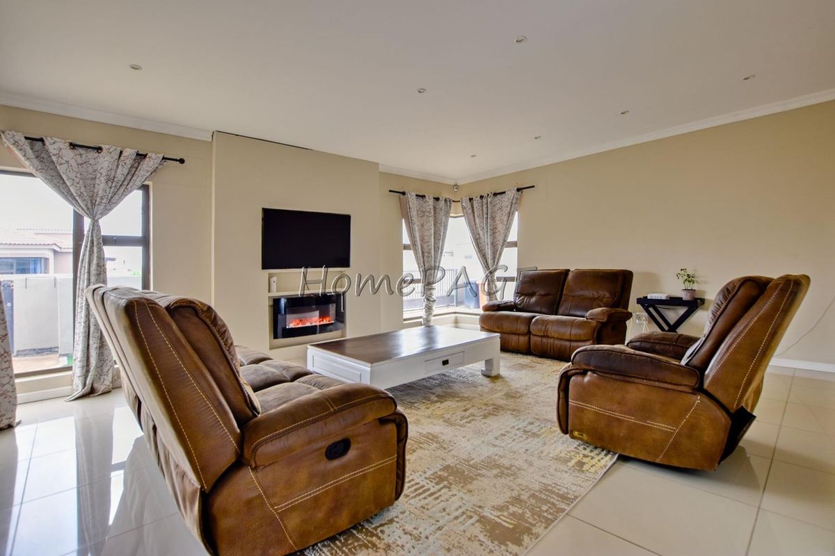 Spacious living room featuring tiled flooring, recessed downlights, and a modern built-in electric fireplace, offering a comfortable and well-lit area.
