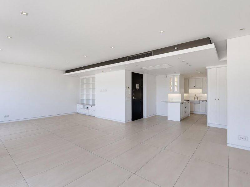 Spacious open-plan living area featuring neutral tiled flooring, recessed lighting, ducted air conditioning, and a modern kitchen with built-in cabinetry.