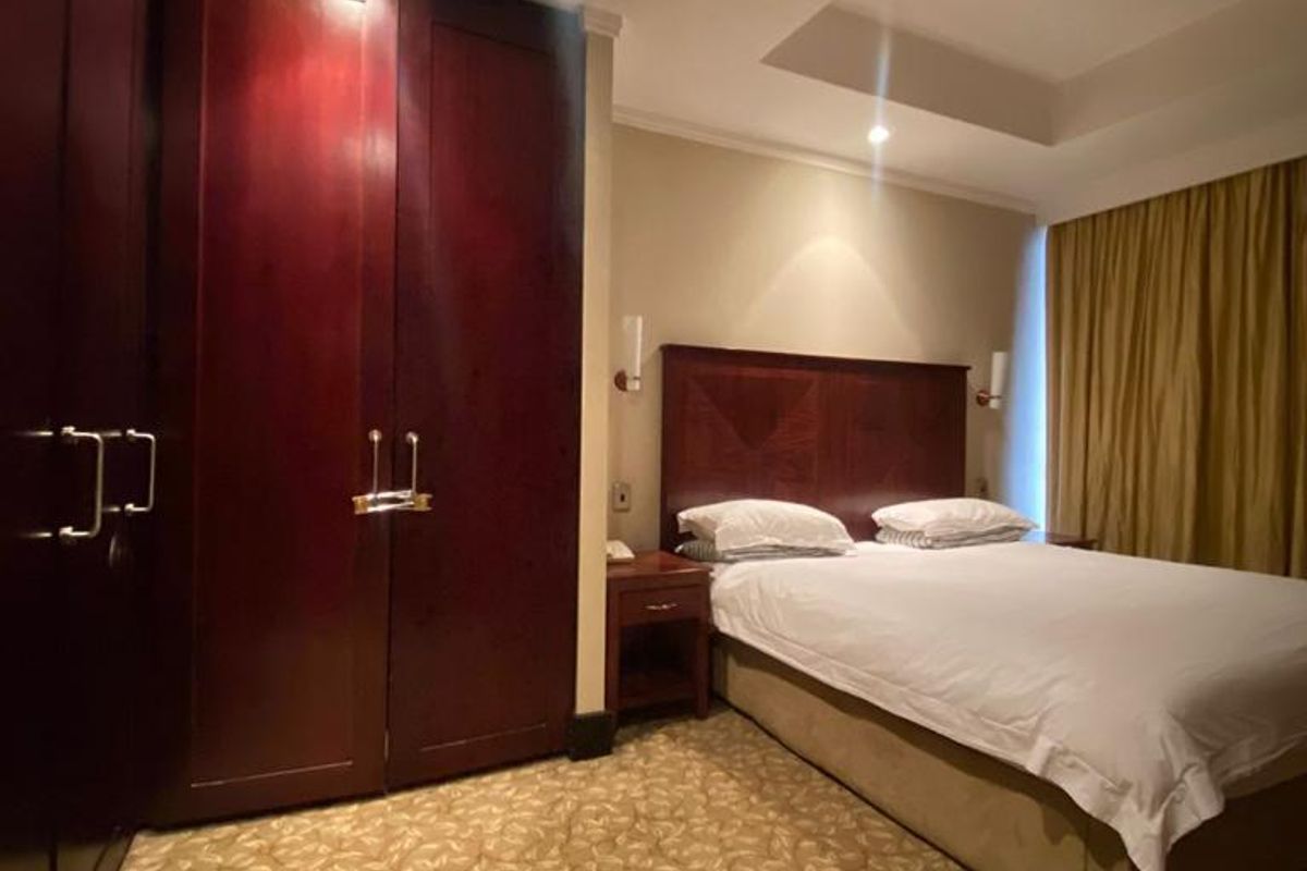 A bedroom featuring built-in dark wood cabinetry, recessed ceiling lighting, and patterned carpeting.