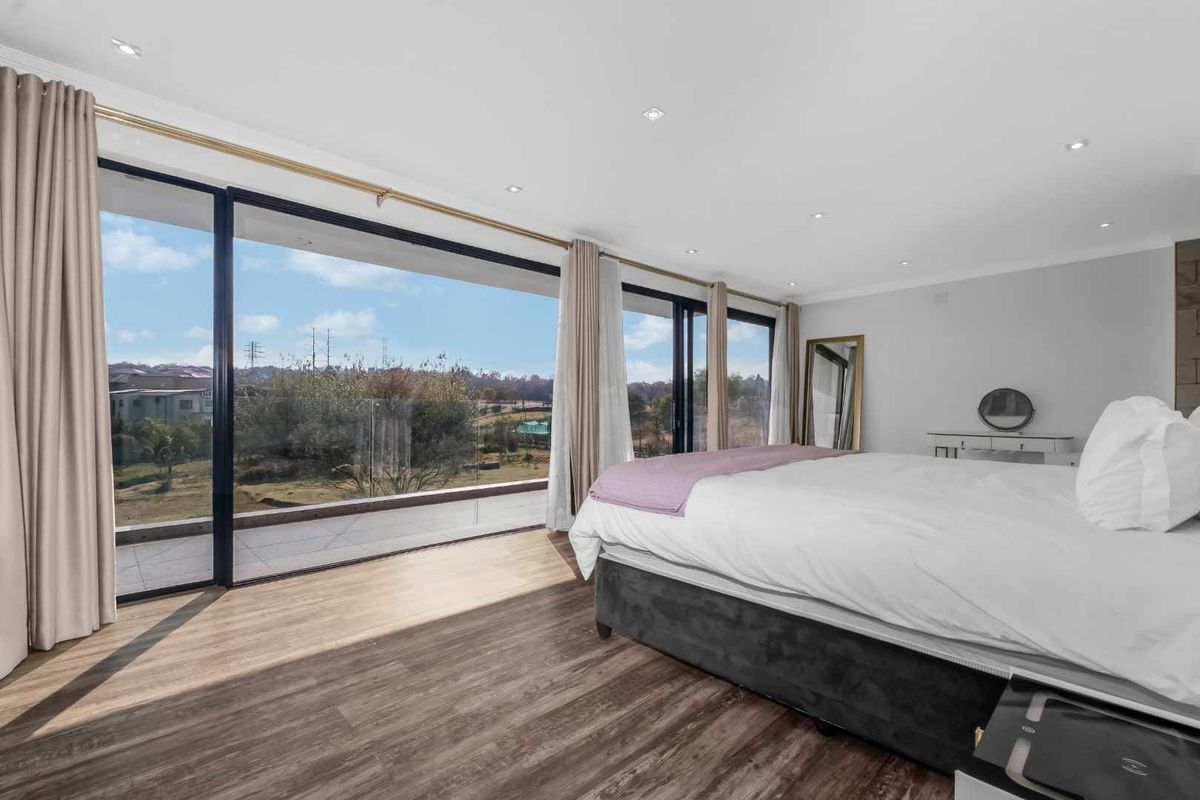 Spacious bedroom featuring laminate flooring, recessed lighting, and large sliding glass doors opening to a balcony with scenic views.