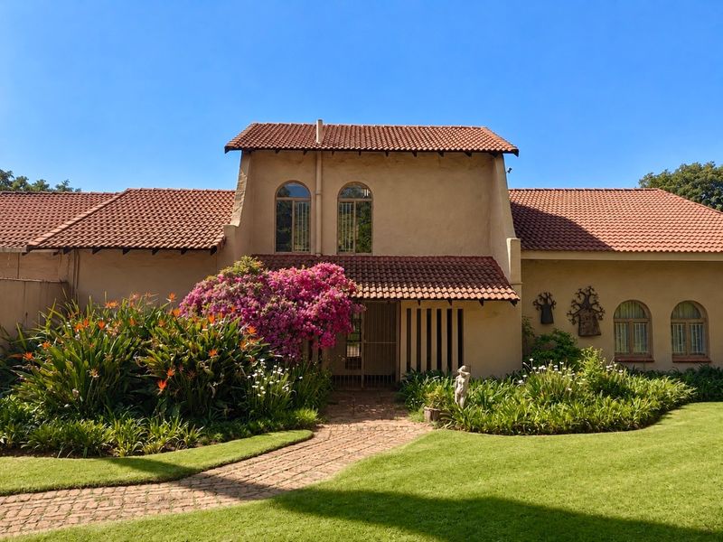 A charming front facade featuring terracotta roof tiles, arched windows, and a well-maintained garden with a brick-paved entrance path.