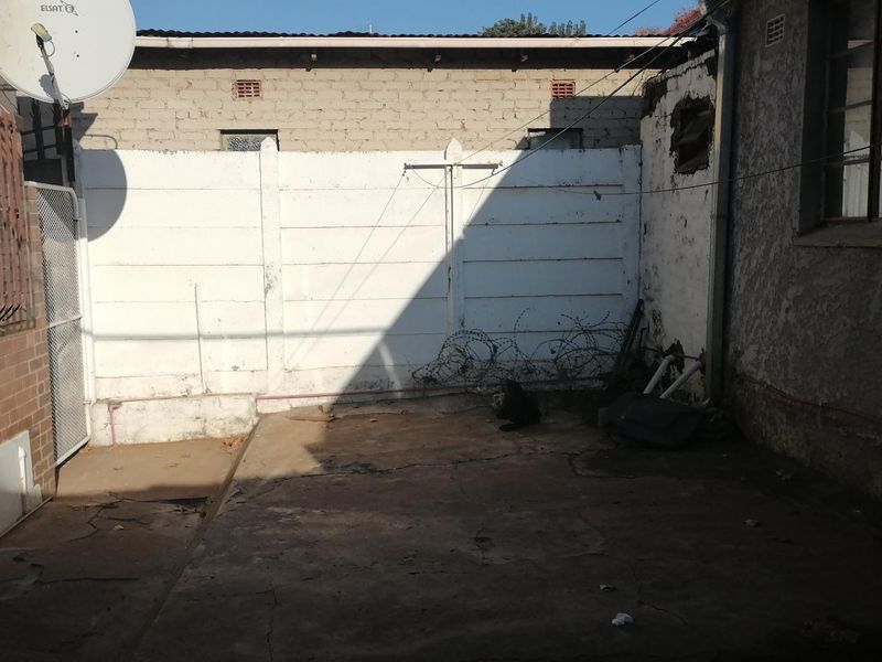 A rear exterior courtyard area featuring a concrete patio, perimeter boundary wall, and exposed building exterior finishes.