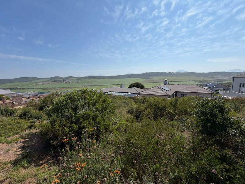 A scenic elevated view overlooking the surrounding landscape and neighboring residential properties, showcasing the natural terrain and open horizon.