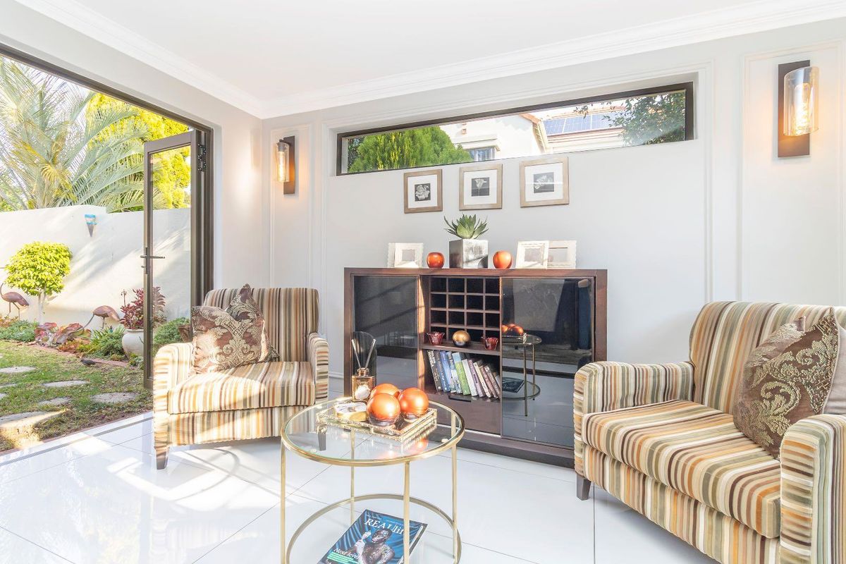 Bright living room featuring polished tile flooring, crown molding, and a large bi-fold door providing seamless access to the garden.