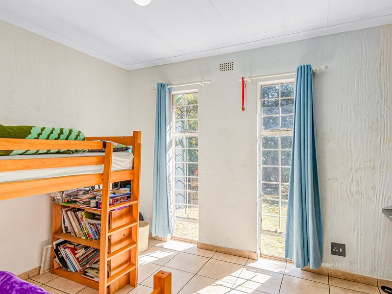 A bedroom featuring tiled flooring and dual sash windows, requiring cosmetic updates to the wall finishes to improve the overall aesthetic.