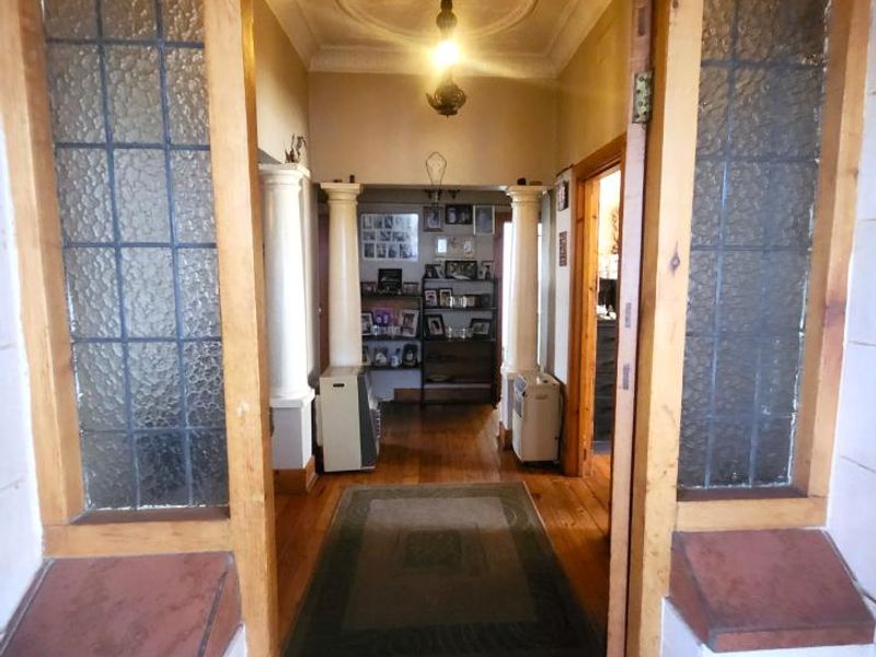Entrance hall featuring original timber flooring, decorative columns, and classic leaded glass sidelights, providing a character-filled transition into the home.