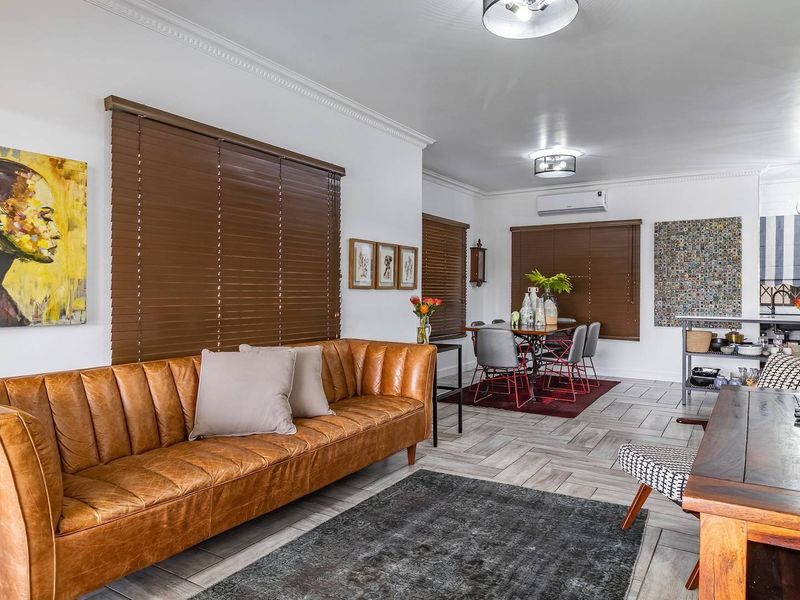 Spacious open-plan living and dining area featuring tiled flooring, split-system air conditioning, and timber venetian blinds throughout.