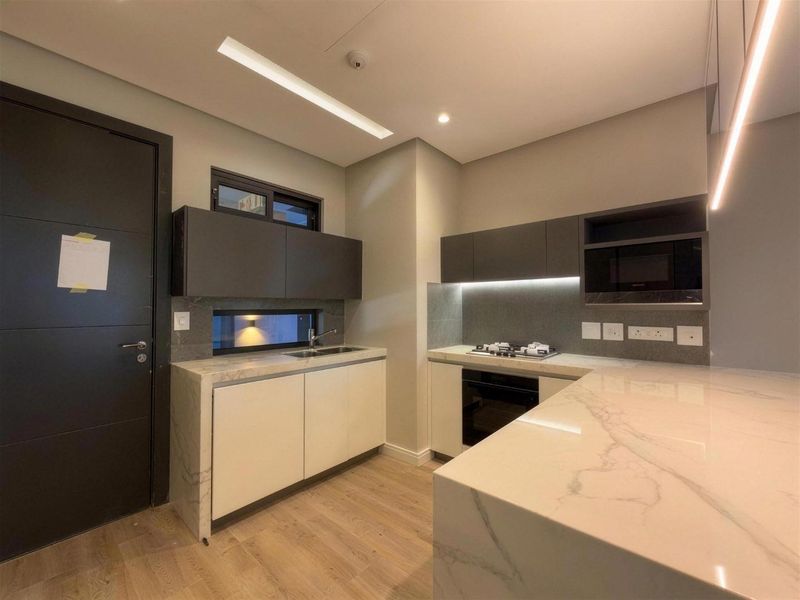Modern kitchen featuring marble-look stone countertops, built-in oven, gas hob, integrated microwave, and sleek cabinetry with under-cabinet lighting.