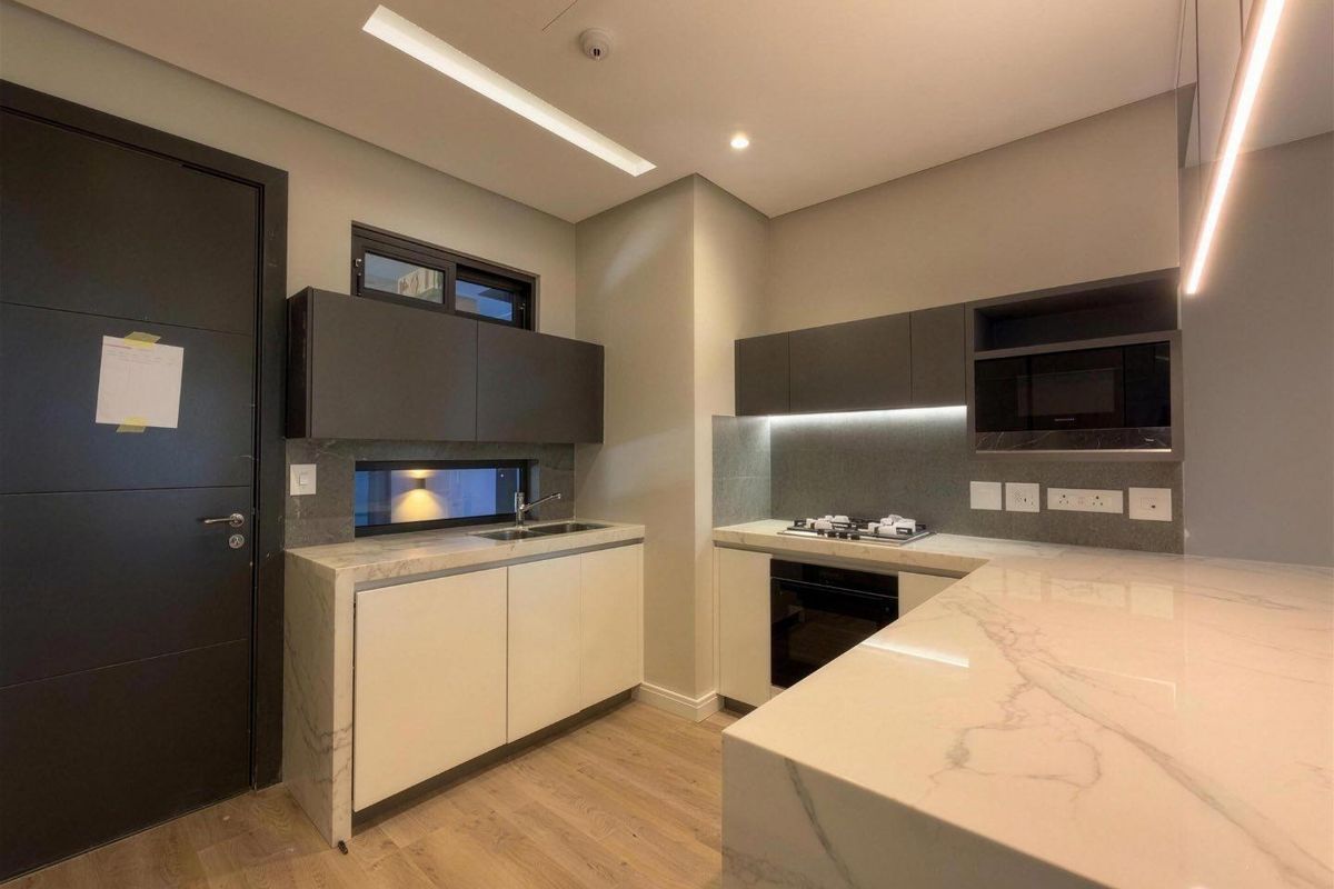 Modern kitchen featuring marble-look stone countertops, built-in oven, gas hob, integrated microwave, and sleek cabinetry with under-cabinet lighting.