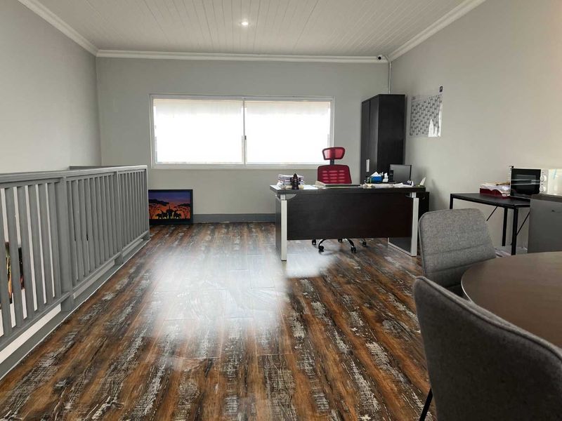 Spacious office area featuring timber-look laminate flooring, a timber balustrade, and a tongue and groove ceiling with recessed lighting.