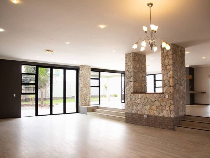 Spacious open-plan living area featuring stone-clad pillars, recessed lighting, and large sliding glass doors that provide seamless access to the outdoor space.
