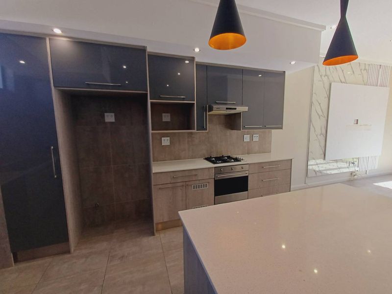 Modern open-plan kitchen featuring sleek grey cabinetry, stone countertops, a gas hob, and a central island, seamlessly integrated into the living space.