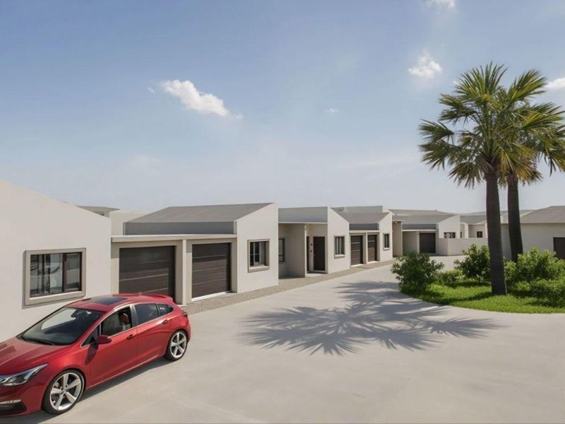 A modern townhouse complex featuring a paved driveway, multiple garage units, and well-maintained landscaped garden areas with palm trees.