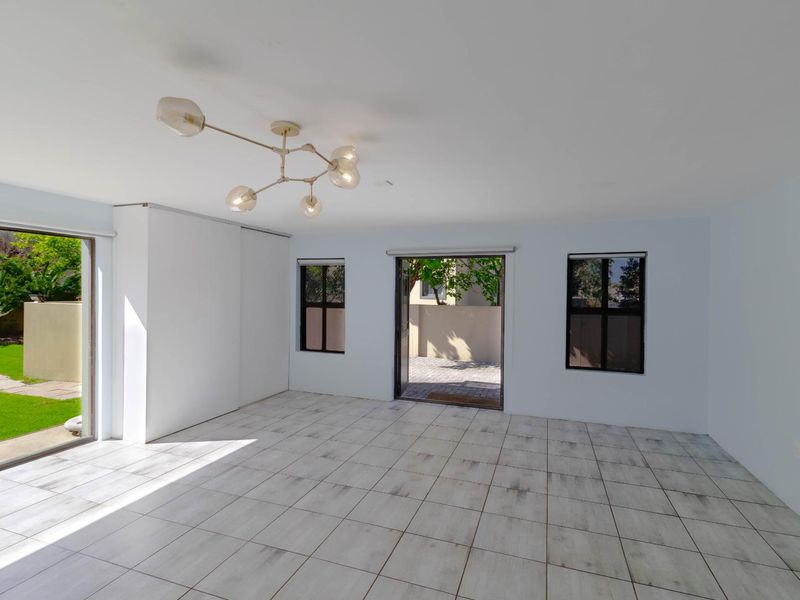 Bright and spacious empty living area featuring tiled flooring, built-in storage, and direct access to the rear garden through sliding glass doors.