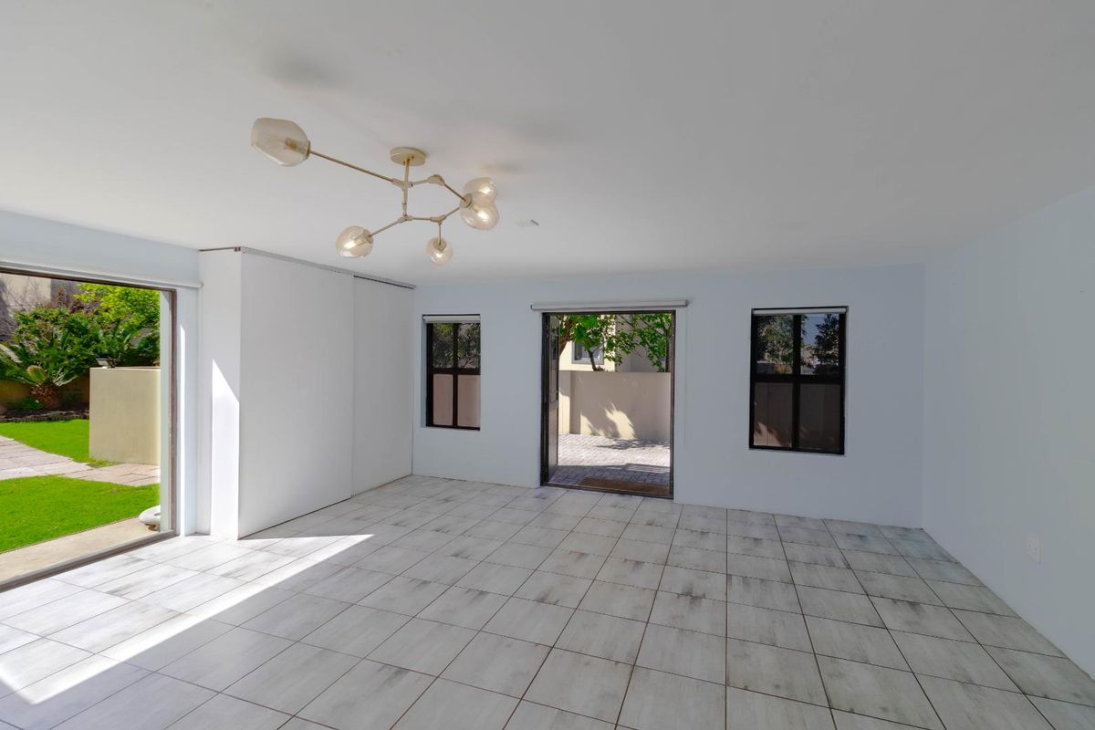 Bright and spacious empty living area featuring tiled flooring, built-in storage, and direct access to the rear garden through sliding glass doors.