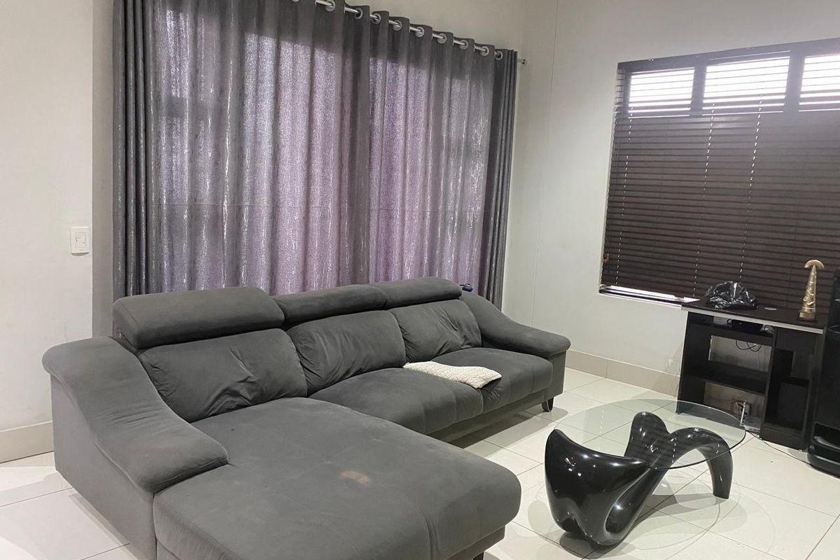 A living room featuring tiled flooring, large window treatments with curtains, and venetian blinds, providing a neutral base for interior design.