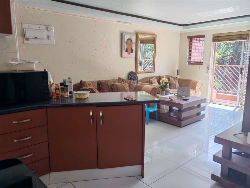 Open plan living area featuring tiled floors, kitchen cabinetry with laminate countertops, and direct access to an outdoor balcony through a sliding glass door.